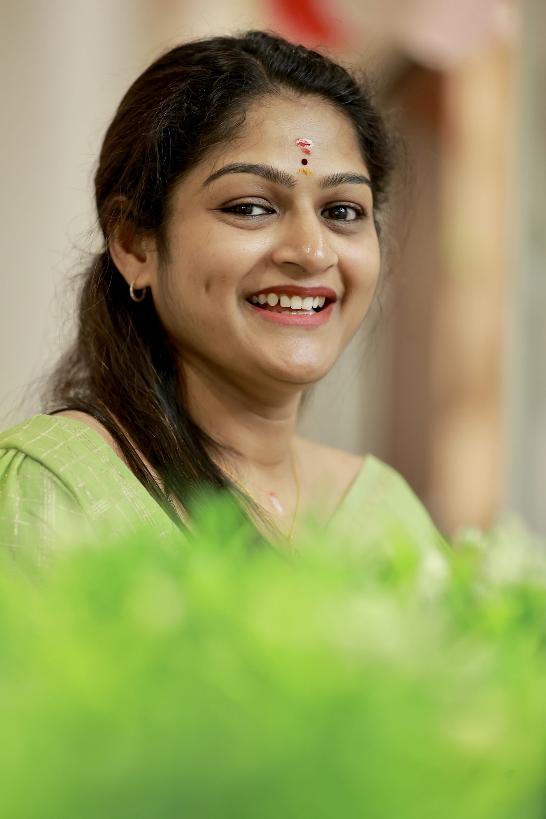 Dhanusree Praveen smiling, in a green saree