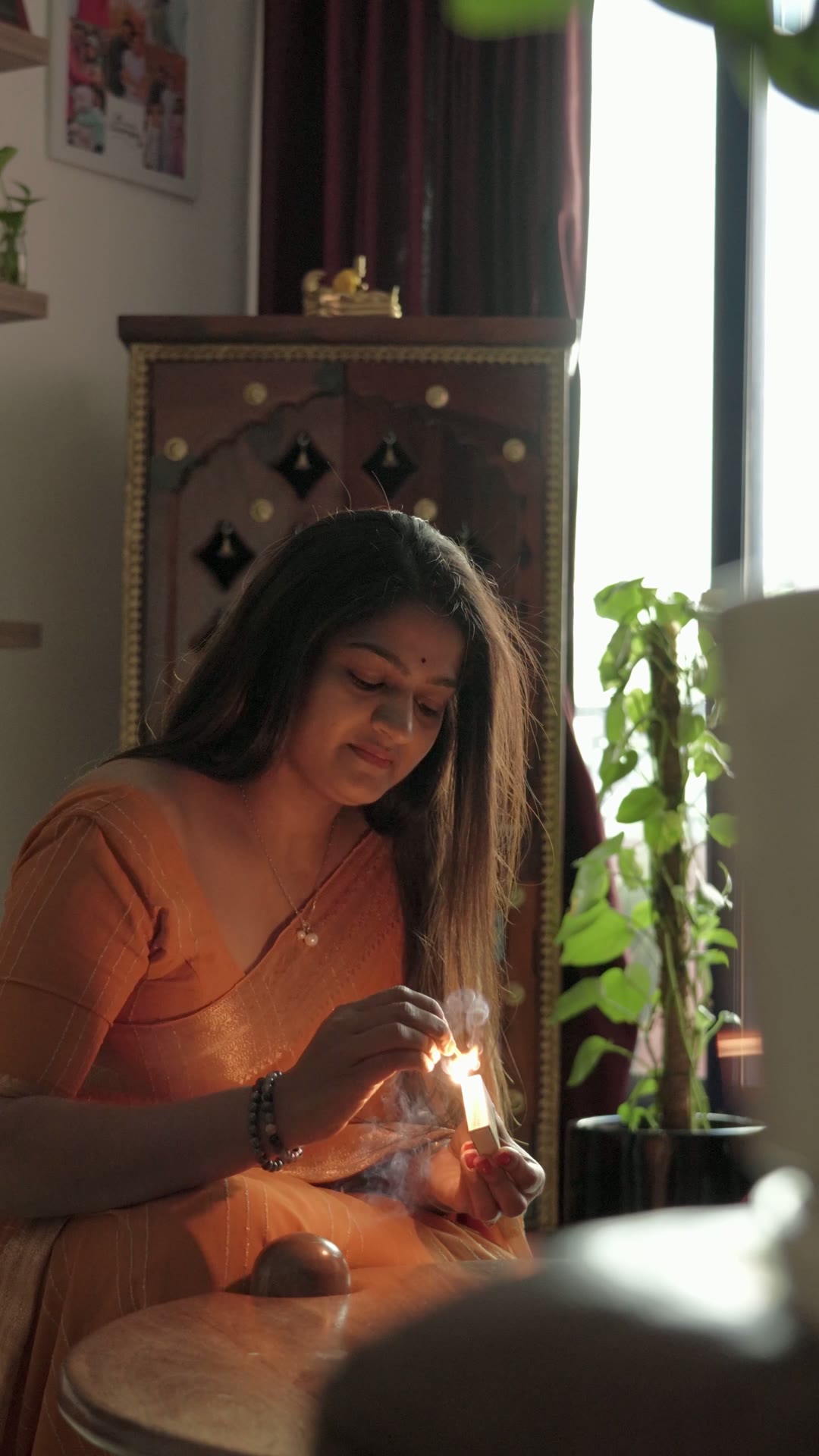 Dhanusree lighting incense beside plants at home