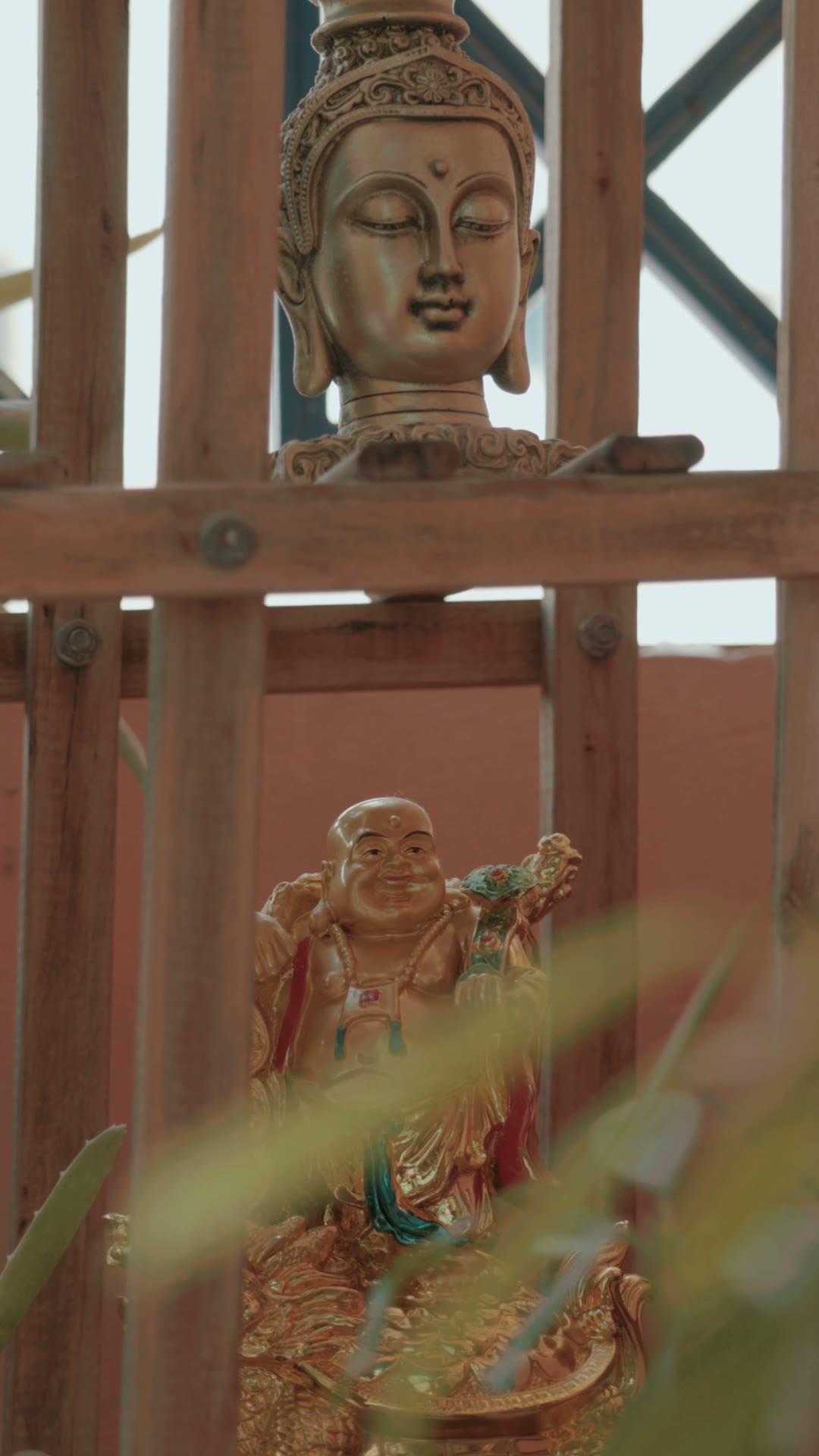 Buddha and Laughing Buddha figures by a sunlit window