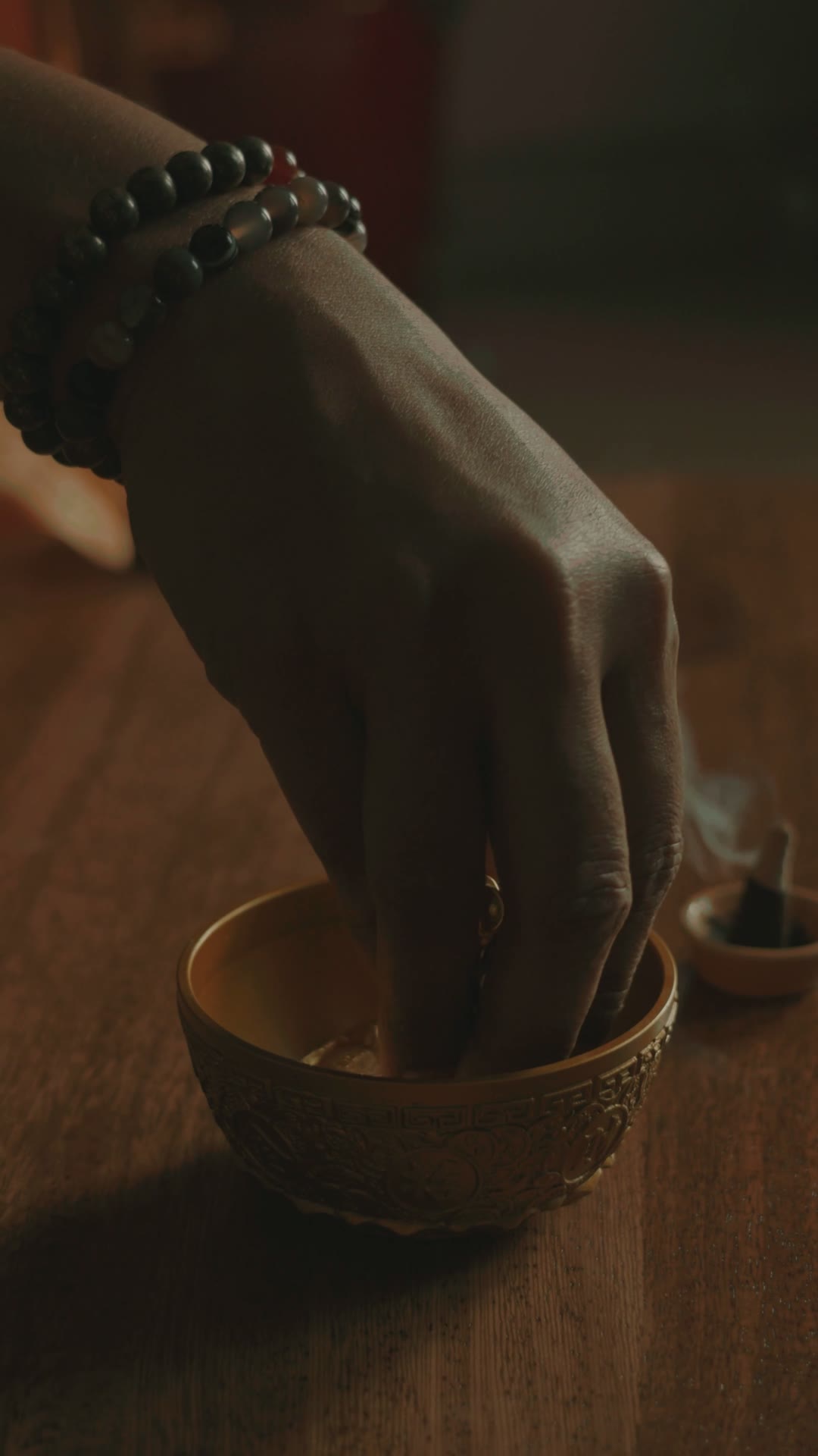 Hand resting in a carved brass bowl
